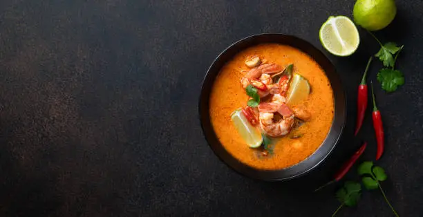 Tom Yum kung Spicy Thai soup with shrimp in a black bowl