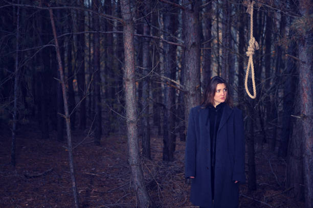 istock brunette woman in coat standing in forest next to gallows 1298975927