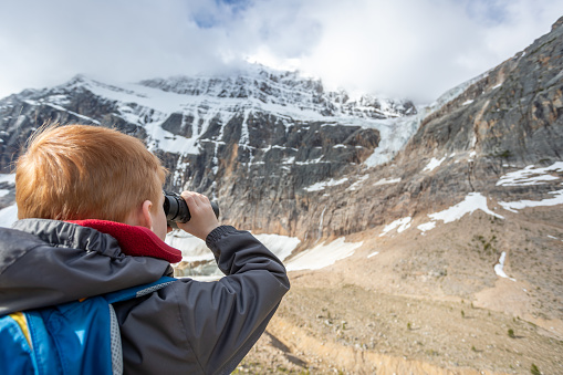 Young Boy Avalanche Watching with Binoculars at Mount Edith Cavell, Alberta, Canada.