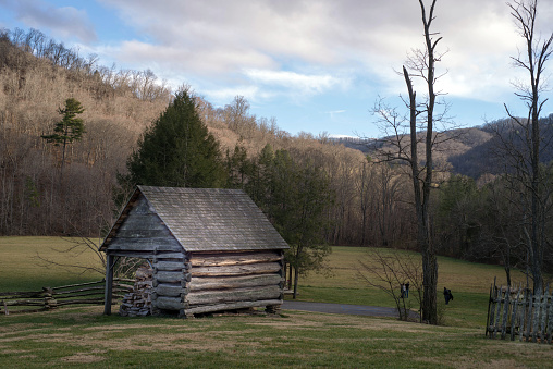 Weaverville, NC, USA.  January 3, 2021.\nOld fashioned scene in North Carolina showing architecture of a bygone era.  The scene is rural with a field, rustic fencing, and a hill with winter trees in the background. A couple people in the background are having a photo shoot.