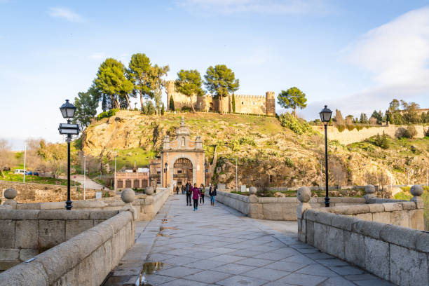 Toledo / Spain - January 23rd, 2020 Tourists Walking over Alcantara Bridge on Sunny Day
