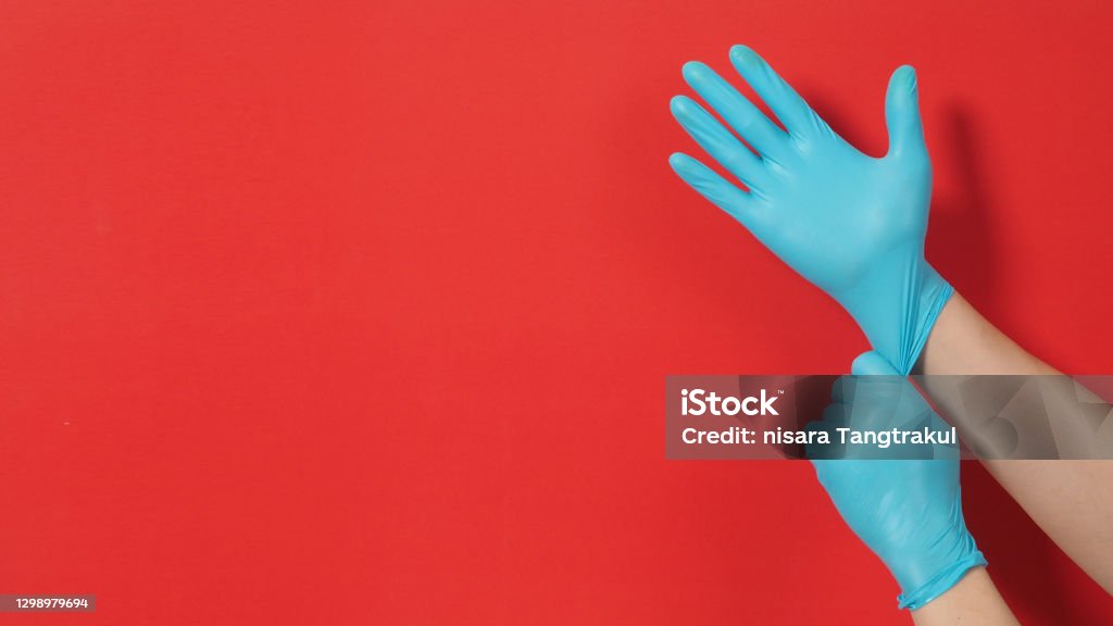 Hand Is Pulling Blue Latex Gloves Or Surgical Gloves On Red Background Hand Is Pulling Blue Latex Gloves Or Surgical Gloves On Red Background
