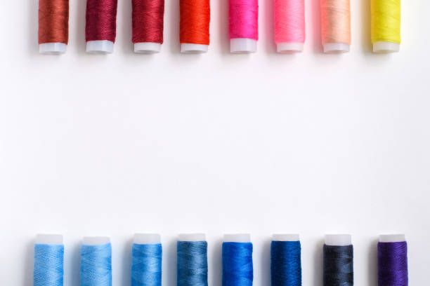 istock Multi-colored spools of thread arranged evenly along the edges on a white background. 1298979782