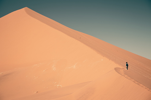 Sand dunes and shadows on orange sand with blue sky