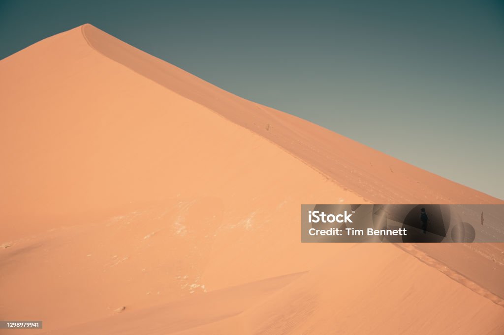 Namibian desert landscape with dramatic warm light Sand dunes and shadows on orange sand with blue sky Adventure Stock Photo
