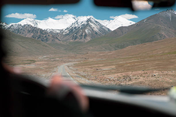 istock Driving the silk road, through empty valley with mountain peaks in background 1298980077