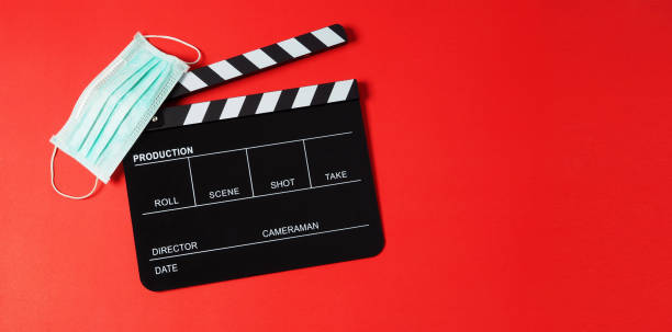 istock Black Clapper board or clapperboard and face mask on red background.It is use in video production or movie and cinema industry. 1298981729