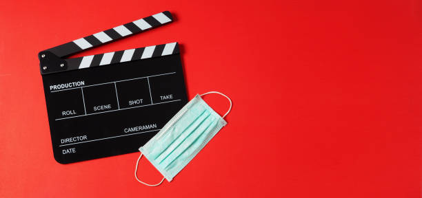 istock Black Clapper board or clapperboard and face mask on red background.It is use in video production or movie and cinema industry. 1298982360