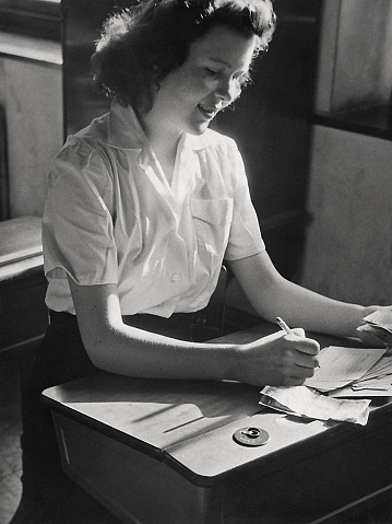 Female high school student sitting a student desk doing bookkeeping in 1944.