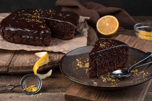 Chocolate cake with icing and lemon zest on a brown wooden background