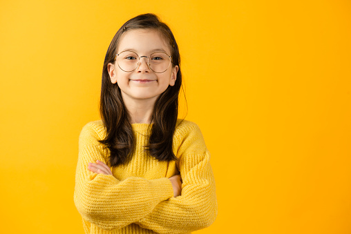 Girl looking at camera, yellow background.