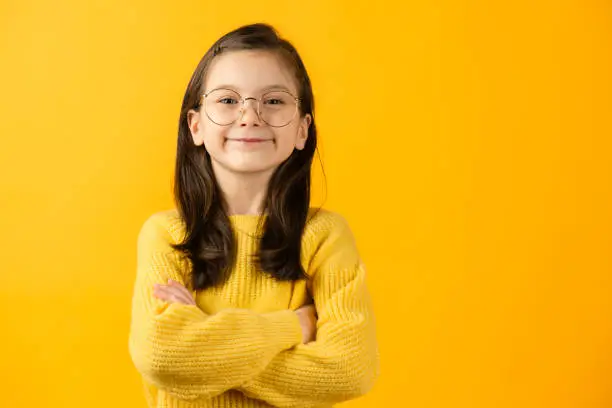 Girl looking at camera, yellow background.