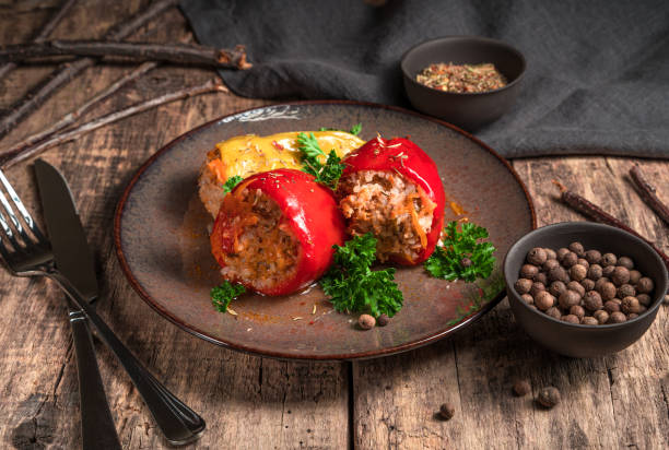 pepper with minced meat on a brown plate, spices and cutlery on a wooden background - brown rice fotos imagens e fotografias de stock