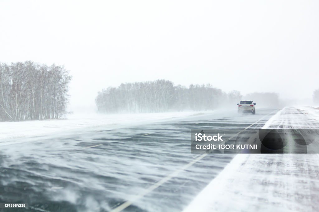 Car moves along an asphalt road during a snow storm. Car moves along an asphalt road during a snow storm Snow Stock Photo