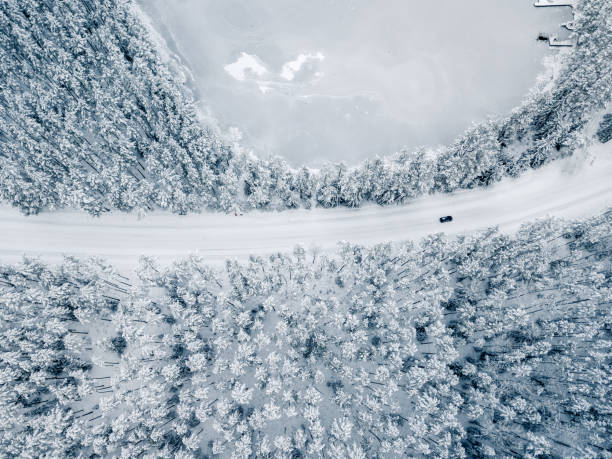 istock Car on Snow Covered Road Between Snowy Trees - Drone View, Top Down Photo 1298984572
