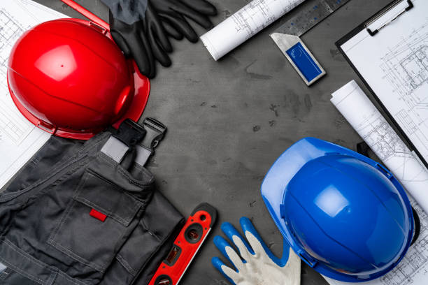 istock Construction worker unifrom, hardhat and blueprints on wooden background 1298987103