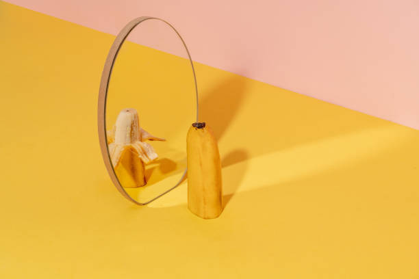metà della banana in uno specchio con una metà messa alla gogna. - pilled foto e immagini stock