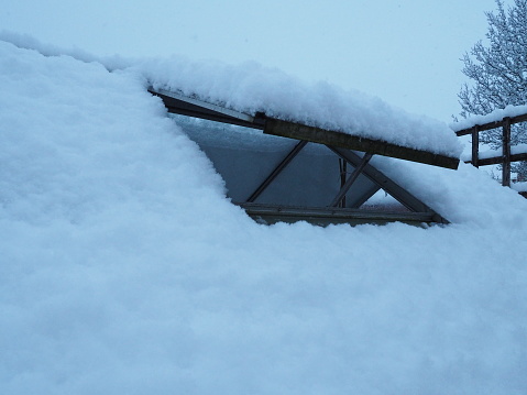 Landscape photo of an open greenhouse window covered in fresh snow
