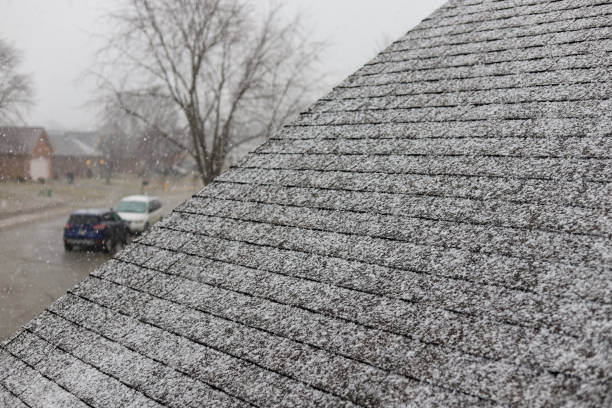Snow on shingles on a roof of a residential home stock photo