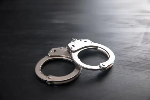 Photo of handcuffs on wooden background