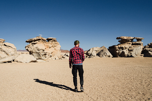 Caucasian man in looking at scenic view of El Árbol De Piedra in Altiplano, Bolivia