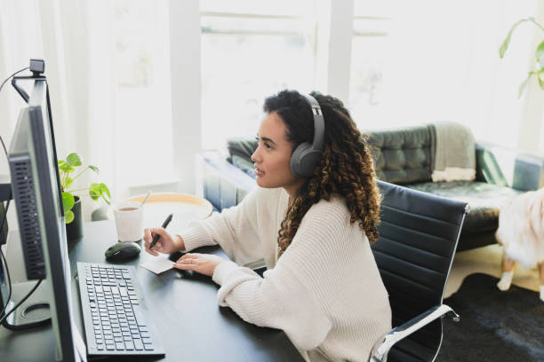istock Woman with headphones takes notes during online class 1298997618