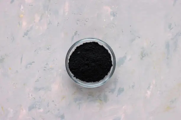 Photo of Black activated charcoal powder in glass bowl