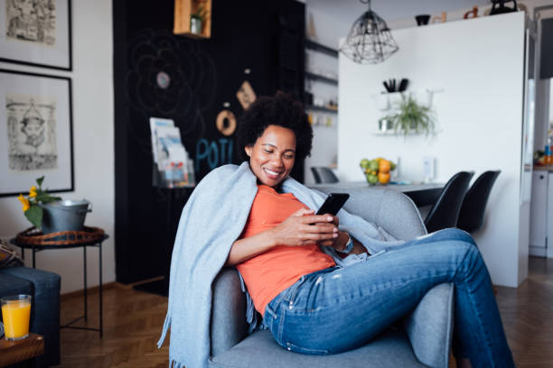 istock One African American woman sitting at home, using a smart phone 1299001731