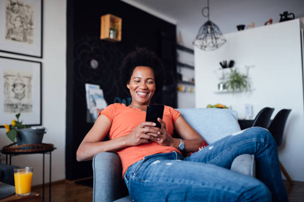 istock One African American woman sitting at home, using a smart phone 1299001738