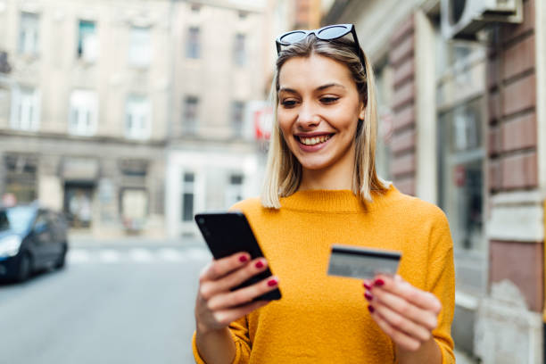 istock Attractive Caucasian woman using a smart phone and a credit card 1299002381