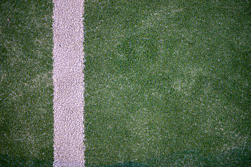 white line detail painted on green artificial synthetic grass with sand dirt