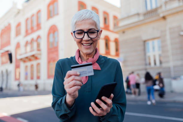 istock Senior Caucasian woman using a smart phone and a credit card 1299003225