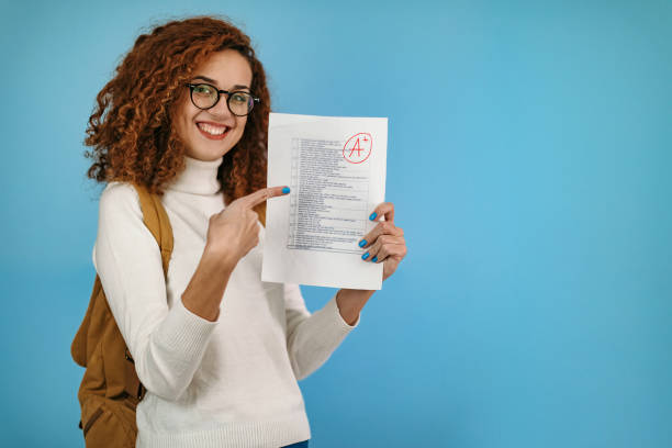I'm good at school Woman standing in front of blue background holding school exam good grades stock pictures, royalty-free photos & images