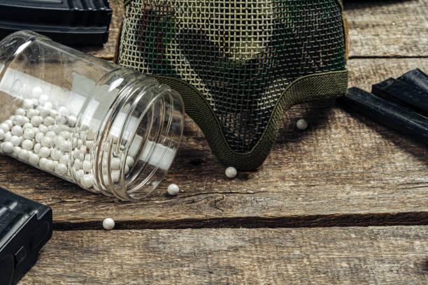 close up of airsoft gun magazine and airsoft balls on wooden background - airsoft gun imagens e fotografias de stock