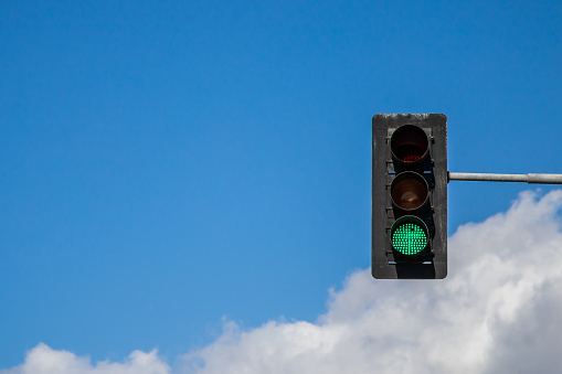 Green traffic light against blue sky