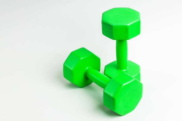 istock green plastic sport dumbbell for strength training over gray background. copy space. exercise equipment for healthy lifestyle 1299008389
