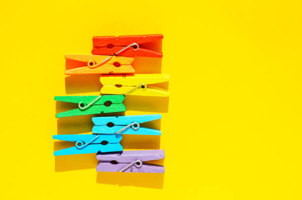 istock Mood-boosting color concept, multi-colored wooden multi-colored clothespins in a row on a yellow paper background. Creative minimalistic design, flat layout, copy of the space 1299012397