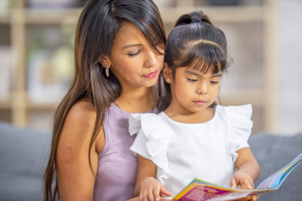 istock Mother and daughter reading a book together 1299012532