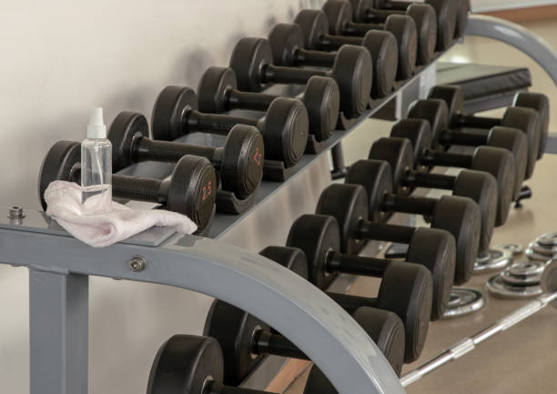 istock Cleaning exercise machines with alcohol sanitizer spray before lifting dumbbells in the gym or fitness. 1299012694