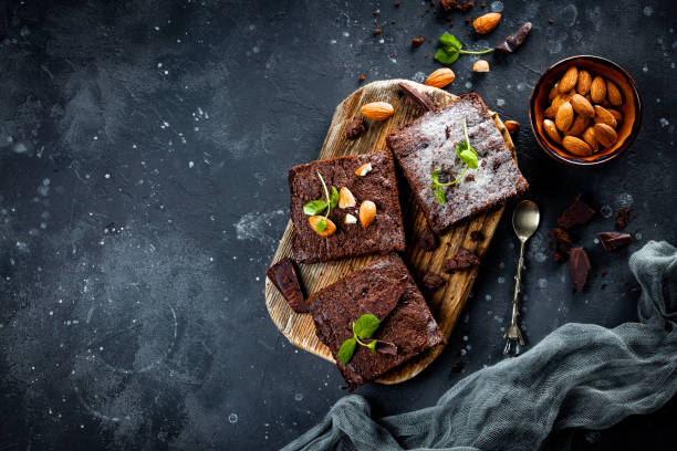 kawałki domowej roboty czekoladowe brownie z miętowymi liśćmi i orzechami na szarym tle, kopisk z góry - food still life sweet food pudding zdjęcia i obrazy z banku zdjęć