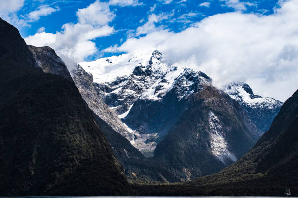 istock Tall snowy mountain with clouds swirling 1299015600