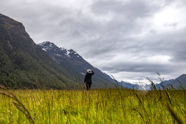 istock Adventurous woman walking in valley with snow capped mountain range background 1299016360