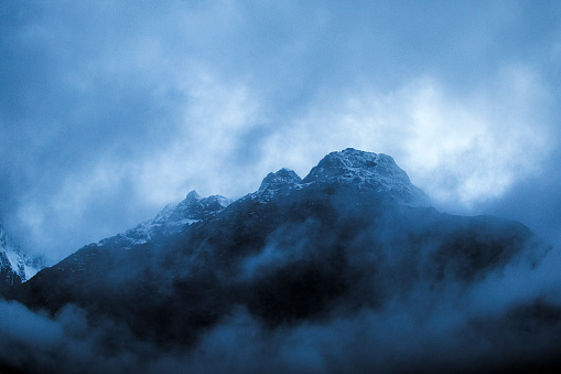 Mountain landscape with rocks and creeping fog. High peaks in the clouds, cold weather. Tourism in the mountains