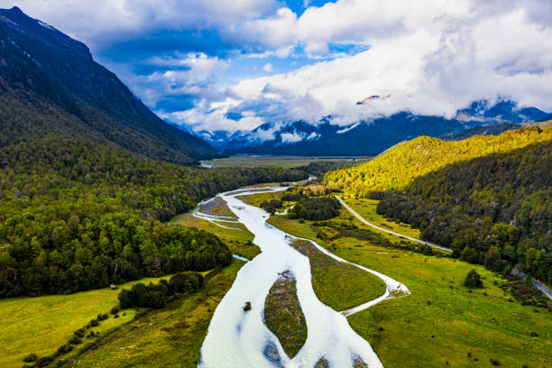 istock River flowing through valleys of green lush pastures surrounded with mountains 1299017692