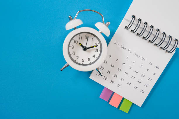 istock white analog alarm clock on white calendar with grunge blue background with copy space, business meeting schedule, travel planning or project milestone and reminder  concept 1299022573