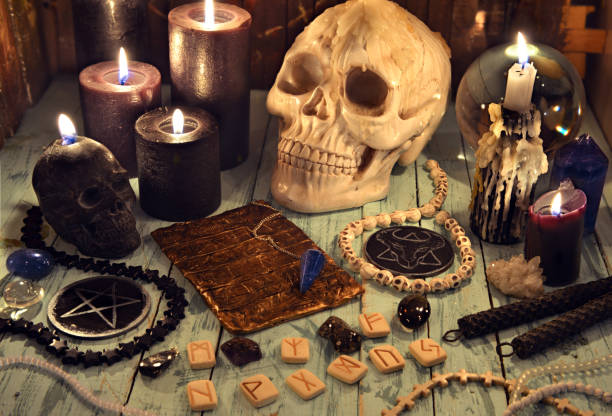 istock Still life with black candles, evil skull, magic objects and runes on witch wooden table. 1299029117
