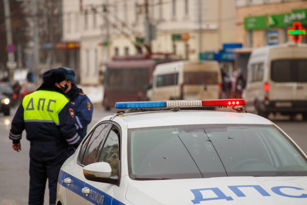 russische straßenpolizisten stehen in der nähe von streifenwagen auf winterstraße - nahaufnahme mit selektivem fokus auf dachlampe. - control clothing image technique image type stock-fotos und bilder