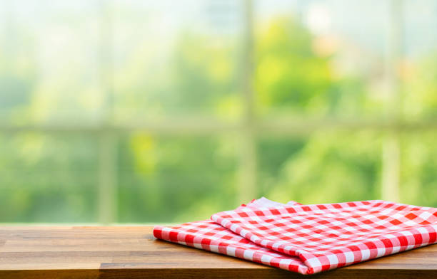 istock Blue checked tablecloth on wood with blur green bokeh from window kitchen background.Summer and picnic concepts. 1299033368