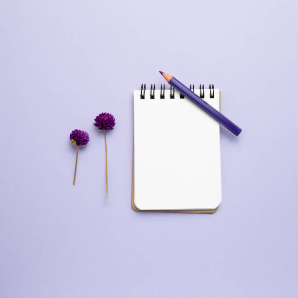 istock Empty notebook, colored pencil, dry flowers on purple background. top view, copy space 1299034950