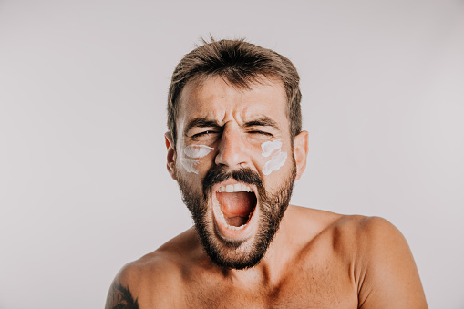 Headshot of an Excited man applying facial skin creme.